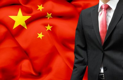 Mężczyzna w garniturze na tle chińskiej flagi
